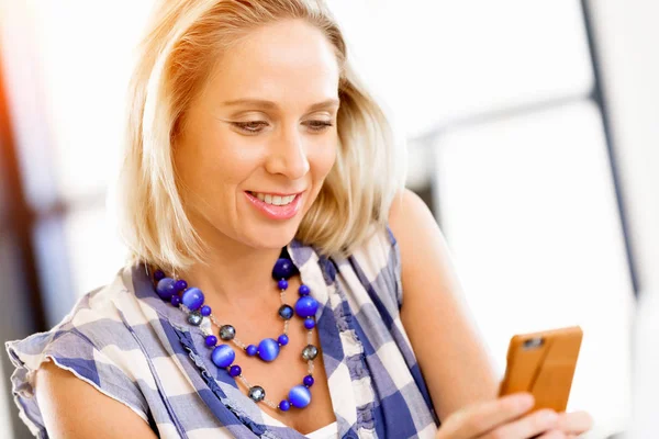 Businesswoman with mobile phone in office — Stock Photo, Image
