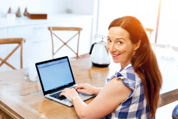 Reife schöne Frau arbeitet auf ihrem Laptop — Stockfoto