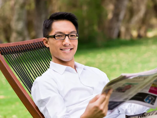 İş adamı parkta bir gazete okuyor