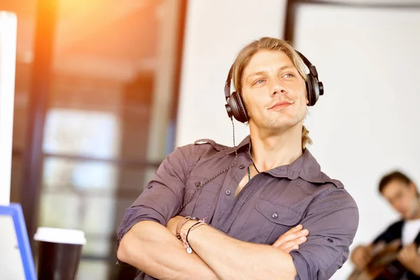 Młody człowiek w biurze ze słuchawkami — Zdjęcie stockowe
