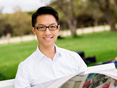 İş adamı parkta bir gazete okuyor