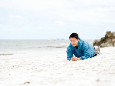 Genç adam sahilde egzersiz yaparak