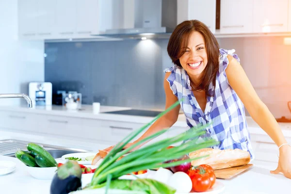 Hermosa mujer de pie en la cocina y sonriendo —  Fotos de Stock