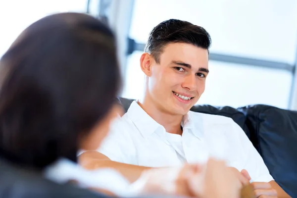 Un uomo sorridente. Coppia seduta a casa e chattare — Foto Stock