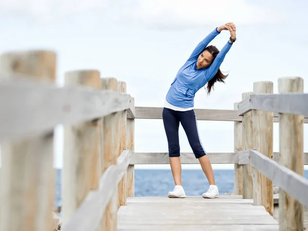 Young woman at the beach doing exercises — Stock Photo, Image