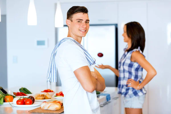 Ung man står i köket och leende — Stockfoto
