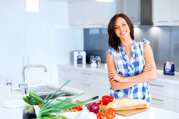 Schöne Frau steht in der Küche und lächelt — Stockfoto