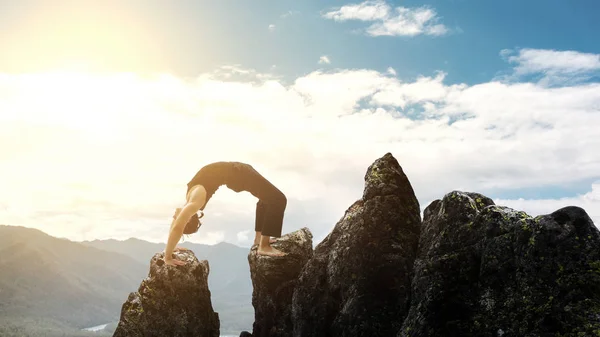 Uomo che fa complesso esercizio di yoga headstand. Incredibile paesaggio Yoga in belle montagne. Pericolosi acrobazie tracciatore in piedi sulle mani sul bordo di una scogliera . — Foto Stock