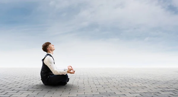 Businessman in lotus pose. Mixed media — Stock Photo, Image