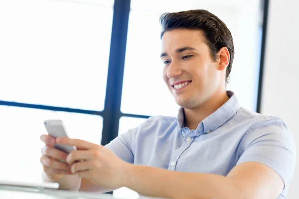 Sebevědomý mladý muž v smart casual oblečení drží telefon — Stock fotografie