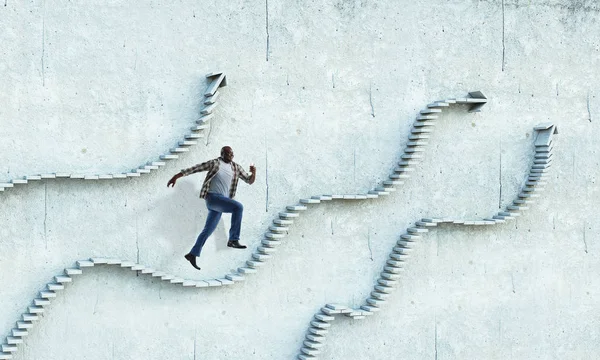 Hombre de negocios negro escalando escaleras de piedra que ilustran el desarrollo profesional y el concepto de éxito. Medios mixtos —  Fotos de Stock