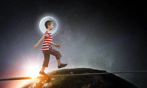 Милый радостный мальчик, шагающий по веревке в космосе. Смешанные медиа — стоковое фото