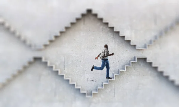 Hombre de negocios negro escalando escaleras de piedra que ilustran el desarrollo profesional y el concepto de éxito. Medios mixtos —  Fotos de Stock