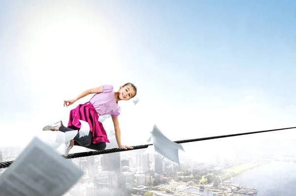 Cute happy little girl on a rope over city. Mixed media — Stock Photo, Image