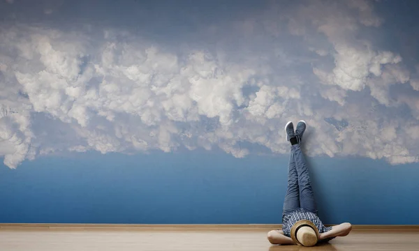 Junger Mann auf dem Boden liegend mit hochgezogenen Beinen an der Wand. Gemischte Medien — Stockfoto