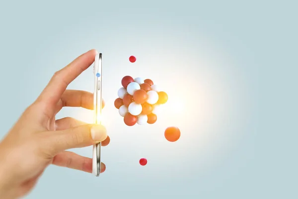 Businessman hand holding a smartphone with a bunch of spheres levitating beside. Mixed media — Stock Photo, Image