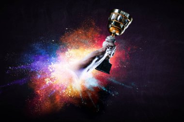 Renkli arka planda şampiyonluk kupasını tutan eller. Karışık ortam