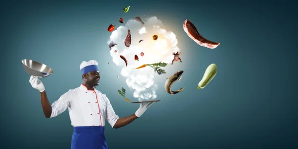 Black man wearing an apron and cooking in action. Mixed media — Stock Photo, Image