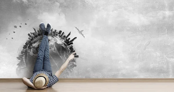 Young man lying on the floor with legs raised up on the wall. Mixed media — Stock Photo, Image