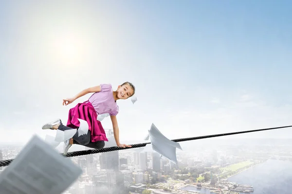 Jolie petite fille heureuse sur une corde au-dessus de la ville. Techniques mixtes — Photo