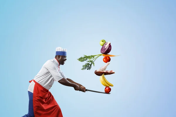 Black man wearing an apron and cooking in action. Mixed media — Stock Photo, Image