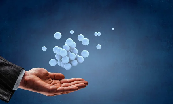 Businessman hand holding a bunch of spheres levitating above. Mixed media — Stock Photo, Image