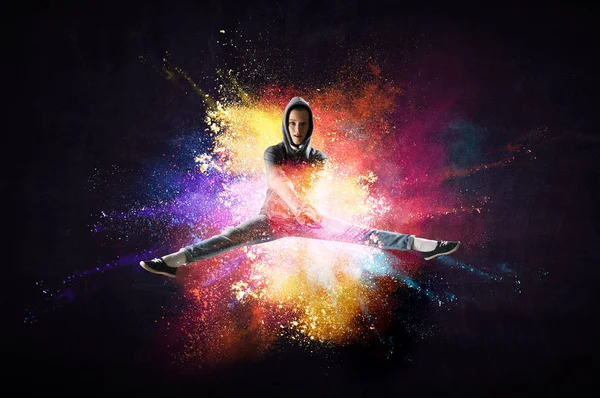 Сучасна жіноча танцівниця стрибає в светрі з барвистим фоном бризок. Змішані носії — стокове фото