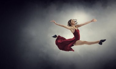 Kırmızı elbiseli genç ve güzel bir bayan dansçı. Karışık ortam