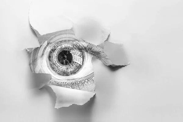 Глаз в дырке рваной бумаги — стоковое фото