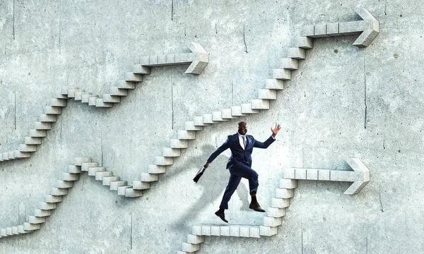 Hombre de negocios negro escalando escaleras de piedra que ilustran el desarrollo profesional y el concepto de éxito. Medios mixtos — Foto de Stock