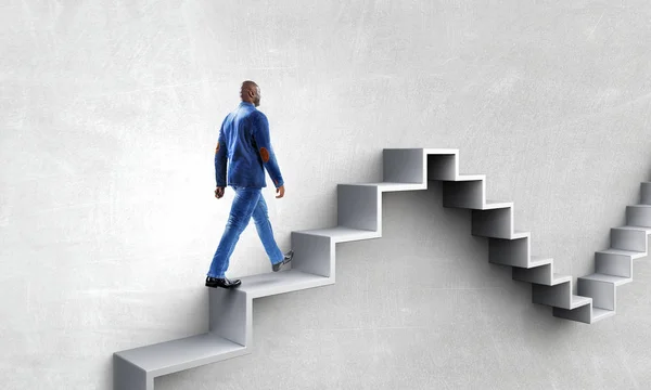 Черный бизнесмен поднимается по каменной лестнице, иллюстрируя развитие карьеры и концепцию успеха. Смешанные медиа — стоковое фото