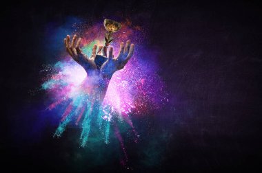 Renkli arka planda şampiyonluk kupasını tutan eller. Karışık ortam