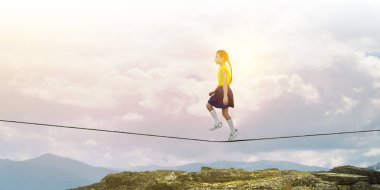 Şehir üzerinde bir halat üzerinde yürüyüş sevimli Neşeli küçük kız. Karışık medya