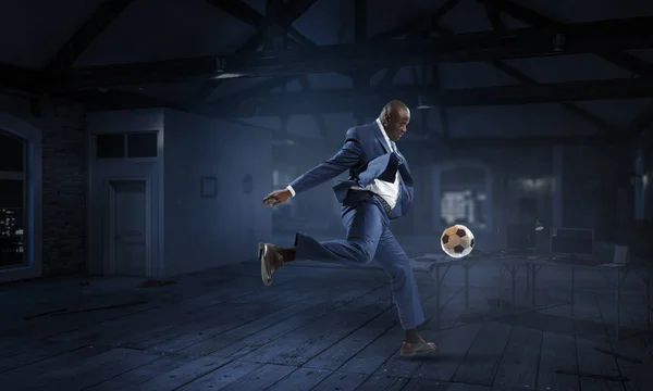 Uomo d'affari nero gioca a calcio in una stanza buia — Foto Stock