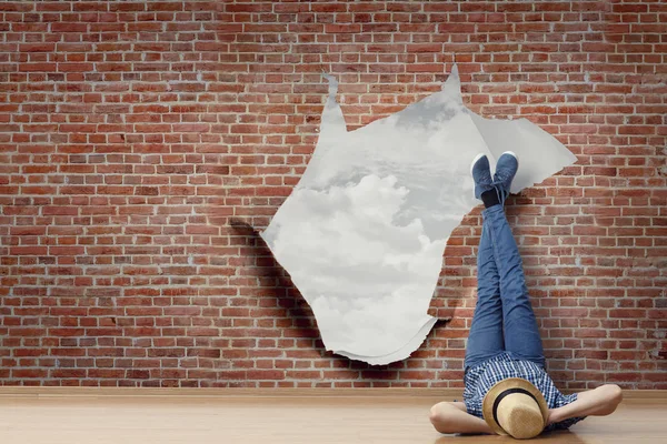 Young man lying on the floor with legs raised up on the wall. Mixed media — Stock Photo, Image