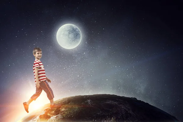 Niedlichen fröhlichen kleinen Jungen, der im Weltraum geht. Gemischte Medien — Stockfoto