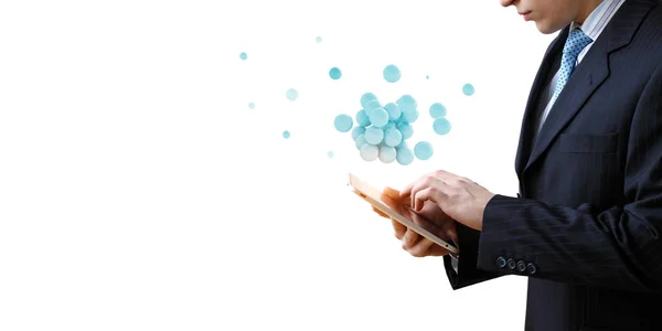 Businessman holding a tabalet with a bunch of spheres levitating above. Mixed media — Stock Photo, Image