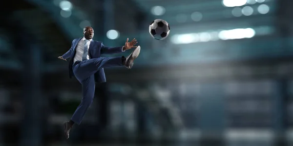 Homem de negócios preto em um terno jogando footbal — Fotografia de Stock