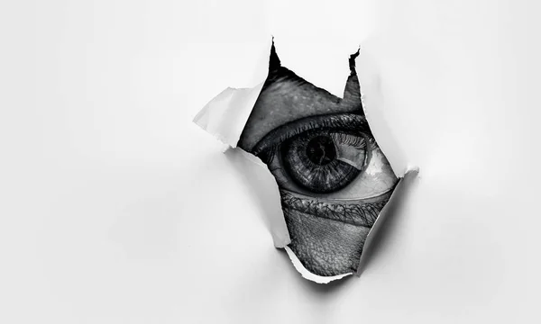 Auge in einem Loch aus zerrissenem Papier — Stockfoto