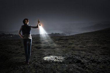 Elinde fener tutan genç bir kadın.