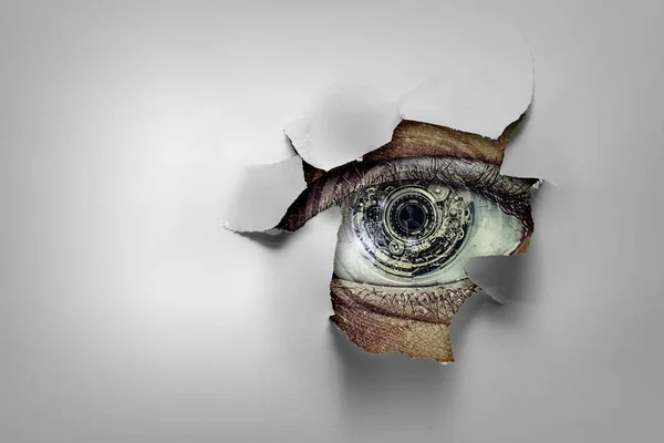 Ojo en un agujero de papel roto —  Fotos de Stock