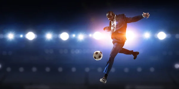 Black businessman in a suit playing footbal