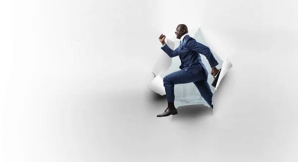 Breakthrough paper hole with a black businessman — Stock Photo, Image