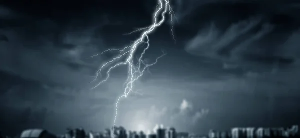 Lightnings at night city with stormy sky — ストック写真