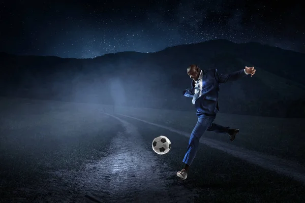 Black businessman in a suit plays football