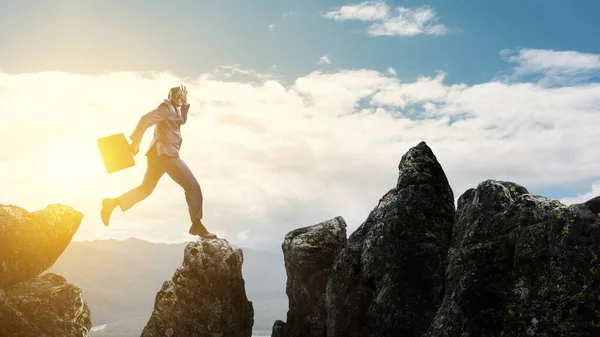 Ευτυχισμένος μαύρος επιχειρηματίας πηδάει πάνω από πέτρες στο βουνό — Φωτογραφία Αρχείου