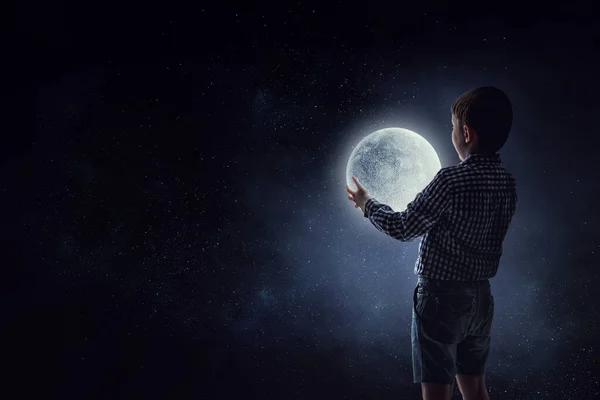 Niño sosteniendo la luna por la noche — Foto de Stock