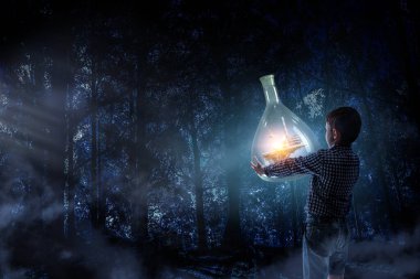 İçinde manzara olan cam matara tutan bir çocuk.