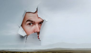 Erkek yüzü kağıttaki delikten geçiyor