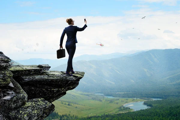 Businesswoman standing against landscape and making selfie — Stock Photo, Image